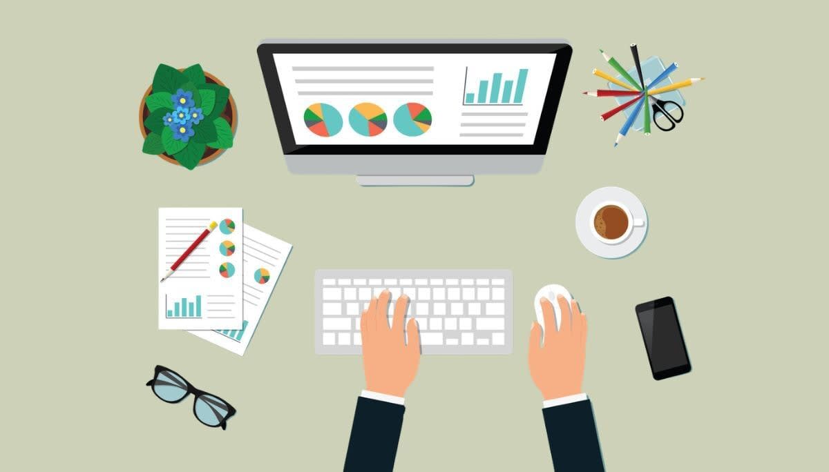 Desk setup with monitor showing graphs, papers, and coffee, representing simple one‑page business plan templates.