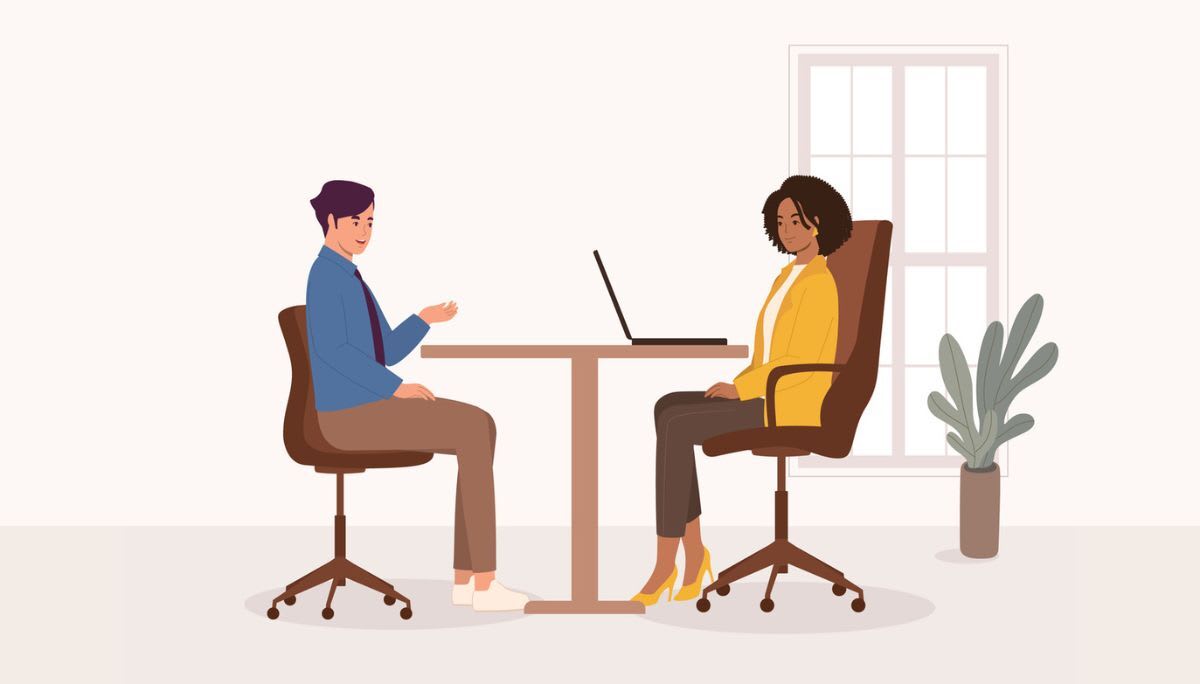 Two professionals seated at desk with laptop.