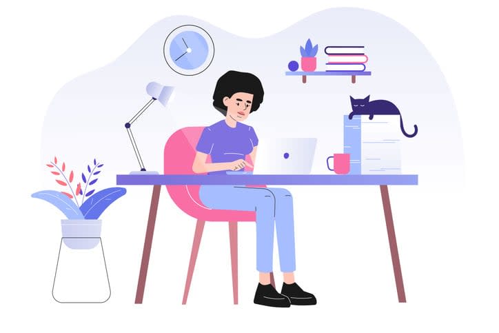 Young woman or freelancer sitting on her a desk with cat and working online with a laptop at home